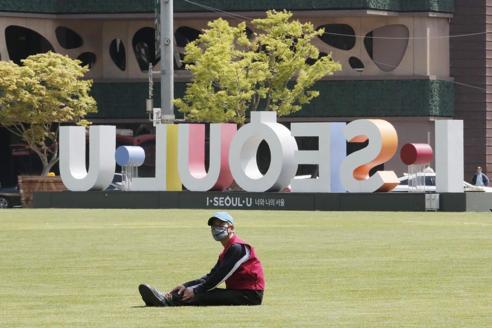 A man wearing a face mask to help protect against the spread of the new coronavirus takes a rest on the grass at Seoul Plaza in Seoul, South Korea, Thursday, May 21, 2020. (AP Photo/Ahn Young-joon)