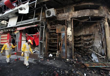 Municipal workers clean the site of a bomb attack in Baghdad's Karrada district February 18, 2014. REUTERS/Ahmed Saad