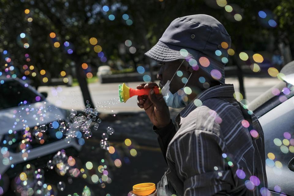 Haitian migrant Philippe hawks bubble blower guns on one of the most congested avenues of Santo Domingo, Dominican Republic, Tuesday, Nov. 23, 2021. An increasing mistreatment of the country’s Haitians, observers say, coincided with the rise of Luis Abinader, who took office as president in August 2020. (AP Photo/Matias Delacroix)