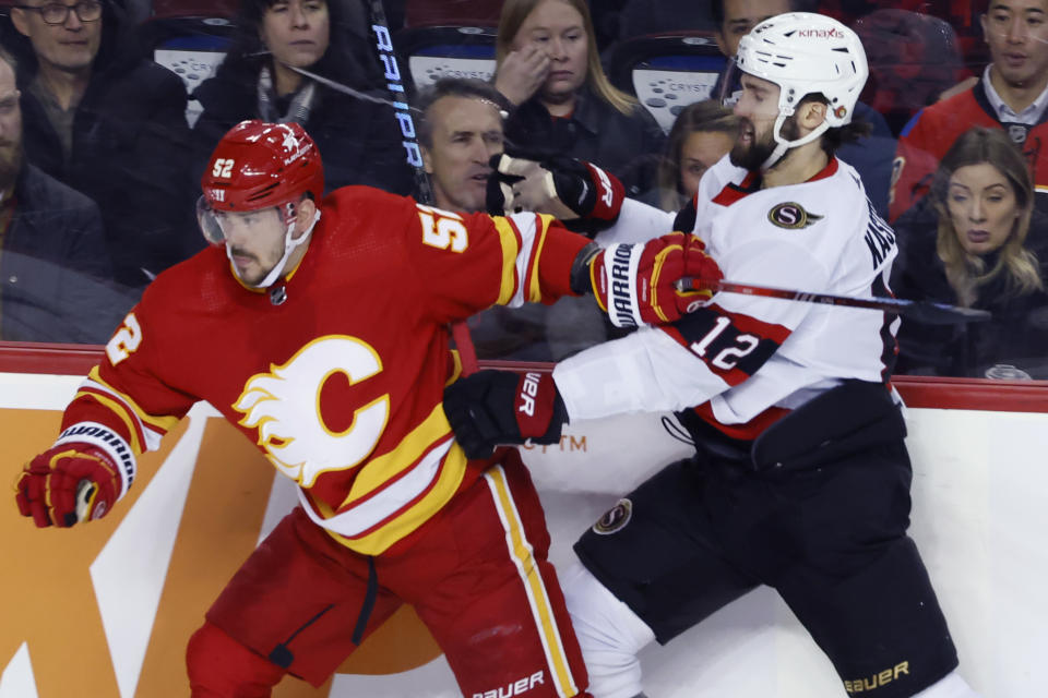 Calgary Flames' MacKenzie Weegar, left, battles with Ottawa Senators' Mark Kastelic during the second period of an NHL hockey game, Tuesday, Jan. 9, 2024 in Calgary, Alberta. (Larry MacDougal/The Canadian Press via AP)