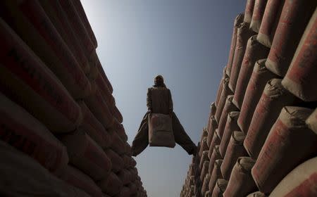 A labourer moves sacks of cement from one truck to another bound for Afghanistan at a transit depot in Peshawar, Pakistan September 16, 2015. REUTERS/Fayaz Aziz