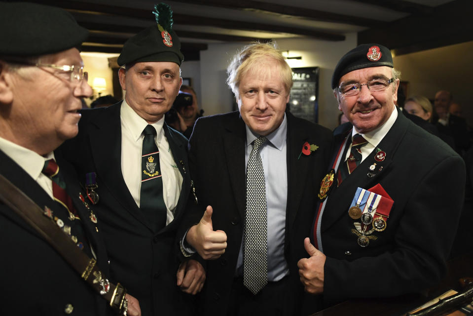 Britain' Prime Minister Boris Johnson, centre, meets with military veterans at the Lych Gate Tavern in Wolverhampton, England, Monday, Nov. 11, 2019 as part of the General Election campaign trail. Britain goes to the polls on Dec. 12. (Stefan Rousseau/PA via AP)
