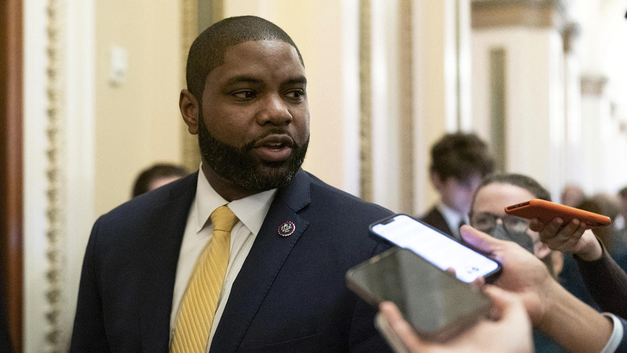 Rep. Byron Donalds, R-Fla., wearing a handsome yellow silk tie, turns to talk to reporters brandishing their cellphones at him, in the corridors of the Capitol.