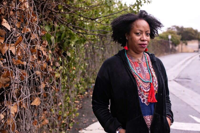 SANTA MONICA, CA - DECEMBER 14: Nichelle Brunson Monroe, stands near a freeway barrier that runs through the area where her family once owned property before it was taken to build the I-10 freeway on Tuesday, Dec. 14, 2021 in Santa Monica, CA. (Jason Armond / Los Angeles Times)