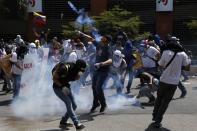 Manifestantes opositores al gobierno de Nicolás Maduro les devuelven las latas de gas lacrimógeno a la policía en medio de los disturbios este jueves 20 de marzo de 2014 en Caracas, Venezuela. REUTERS/Carlos Garcia Rawlins