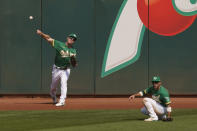 Oakland Athletics left fielder Mark Canha, left, throws the ball to the infield after making a catch at the wall hit by Chicago White Sox's Yoan Moncada during the third inning of Game 2 of an American League wild-card baseball series Wednesday, Sept. 30, 2020, in Oakland, Calif. Center fielder Ramon Laureano, right, backs up the play. (AP Photo/Eric Risberg)