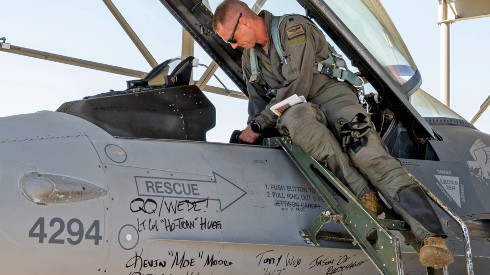 A member of the 309th Fighter Squadron prepares to fly a retiring Block 25 F-16 at Luke Air Force Base, Arizona, on September 6, 2022. Signatures from commanders, honorary commanders, and other members of the squadron cover the aircraft for its final send-off. <em>U.S. Air Force photo by Senior Airman David Busby</em>