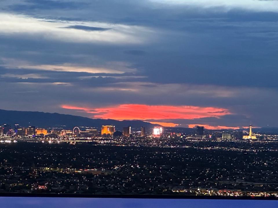 A view of the night sky above Las Vegas, where the setting sun has cast a bright red light against the cloudy sky.