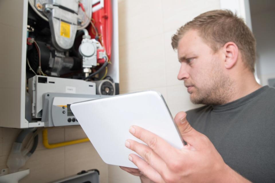 Man using digital tablet to repair furnace.