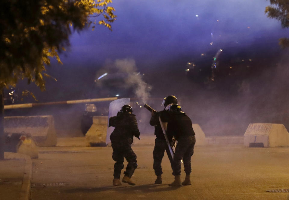 Riot policemen fire tear gas against the supporters of the Shiite Hezbollah and Amal Movement groups, who are trying to attack the anti-government protesters squares, in Beirut, Lebanon, Wednesday, Dec. 11, 2019. Protesters are demanding a government made up of technocrats that would immediately get to work on the necessary reforms to address the economy. (AP Photo/Hussein Malla)