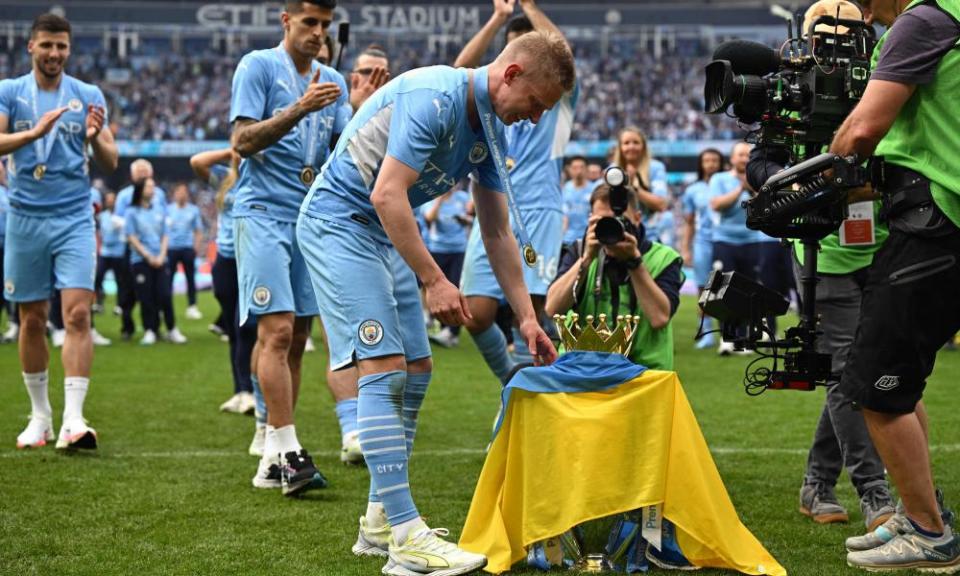 Oleksandr Zinchenko places the flag of Ukraine on the Premier League trophy.