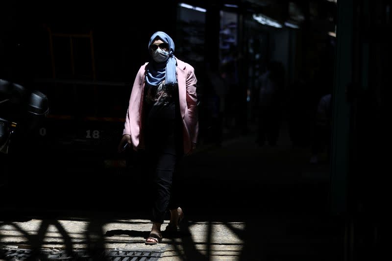 A woman wearing a face mask to help fight the spread of the coronavirus disease (COVID-19) walks past shops in a market in Jerusalem's Old City