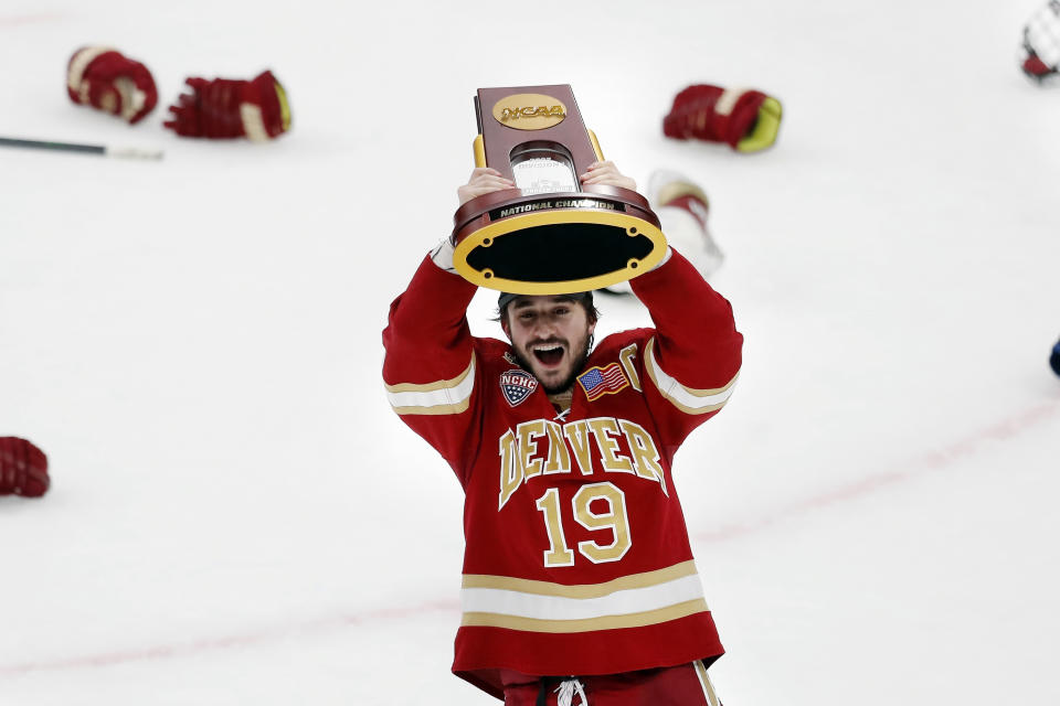 FILE - Denver's Cole Guttman holds up the trophy after Denver defeated Minnesota State in the NCAA men's Frozen Four championship college hockey game April 9, 2022, in Boston. The Mile High City is now home to the Stanley Cup, NCAA and national high school champions. (AP Photo/Michael Dwyer, File)