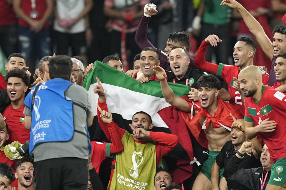 Morocco's team makes a group photo on the pitch, holding the Palestinian flag, after winning the World Cup round of 16 soccer match between Morocco and Spain, at the Education City Stadium in Al Rayyan, Qatar, Tuesday, Dec. 6, 2022. (AP Photo/Martin Meissner)