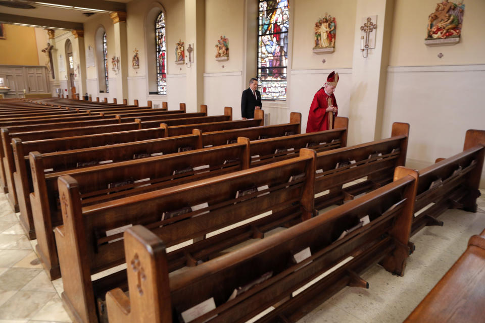 Archbishop Gregory Aymond walks through St. Louis Cathedral, without any congregants, to celebrate Good Friday services in in New Orleans, Friday, April 10, 2020. The service was live streamed due to the new coronavirus pandemic. (AP Photo/Gerald Herbert)