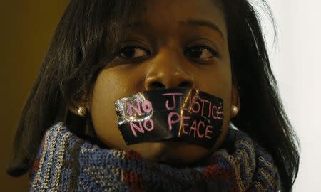 A protester wears tape over her mouth during a silent demonstration against what they say is police brutality after the Ferguson shooting of Michael Brown, an unarmed black teenager, by a white police officer, in St. Louis, Missouri, March 14, 2015. REUTERS/Jim Young