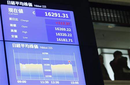 People stand near a monitor displaying Japan's Nikkei average after a ceremony marking the end of trading in 2013 at the Tokyo Stock Exchange (TSE) in Tokyo December 30, 2013. REUTERS/Yuya Shino