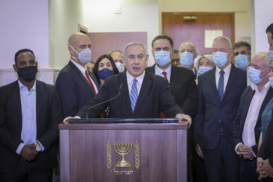 POOL - In this Sunday, May 24, 2020 photo, Israeli Prime Minister Benjamin Netanyahu accompanied by members of his Likud Party in masks delivers a statement before entering the district court in Jerusalem. Benjamin Netanyahu's fulminating tirade against Israel's legal system on the steps of a Jerusalem courthouse managed to even overshadow the opening of his historic corruption trial. Surrounded by loyal deputies, and with hundreds of impassioned supporters cheering him outside and echoing his charges, Netanyahu's onslaught capped a years-long campaign that has bitterly divided the country and raised fears of irreparably tearing apart the delicate fabric of Israeli society. (AP Photo/Yonatan Sindel/Pool Photo via AP)