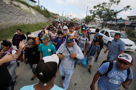 A man carries a child as he walks with other Hondurans fleeing poverty and violence as they move in a caravan toward the United States, in the west side of Honduras October 14, 2018. REUTERS/ Jorge Cabrera