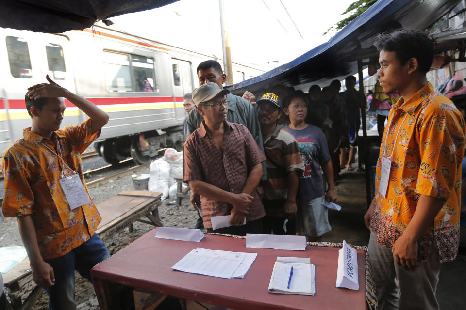 Indonesians queue up to cast their votes during the election near a railway track at a slum in Jakarta, Indonesia, Wednesday, April 17, 2019. Voting is underway across Indonesia in presidential and legislative elections Wednesday after a campaign that pitted the moderate incumbent against an ultranationalist former general. (AP Photo/Tatan Syuflana)