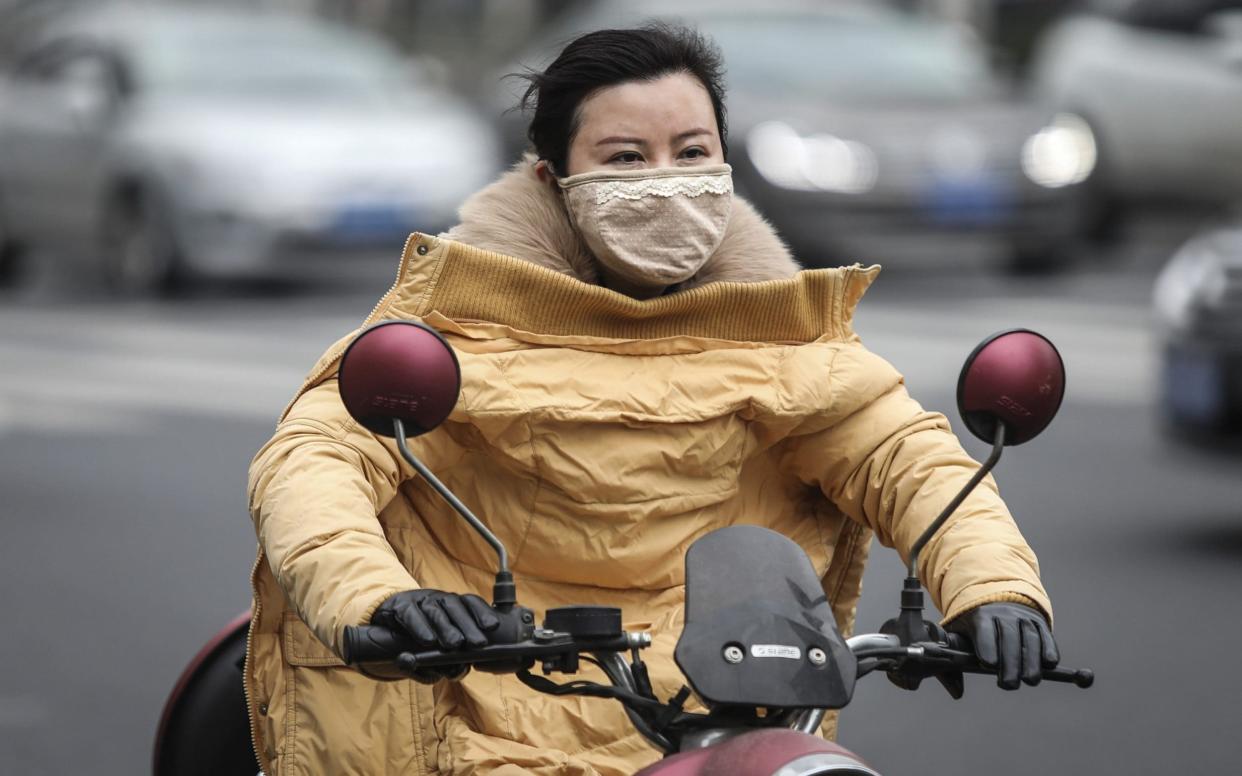  A woman wears a mask while riding an electric bicycle near the closed Huanan Seafood Wholesale Market, which has been linked to cases of coronavirus - Getty Images AsiaPac