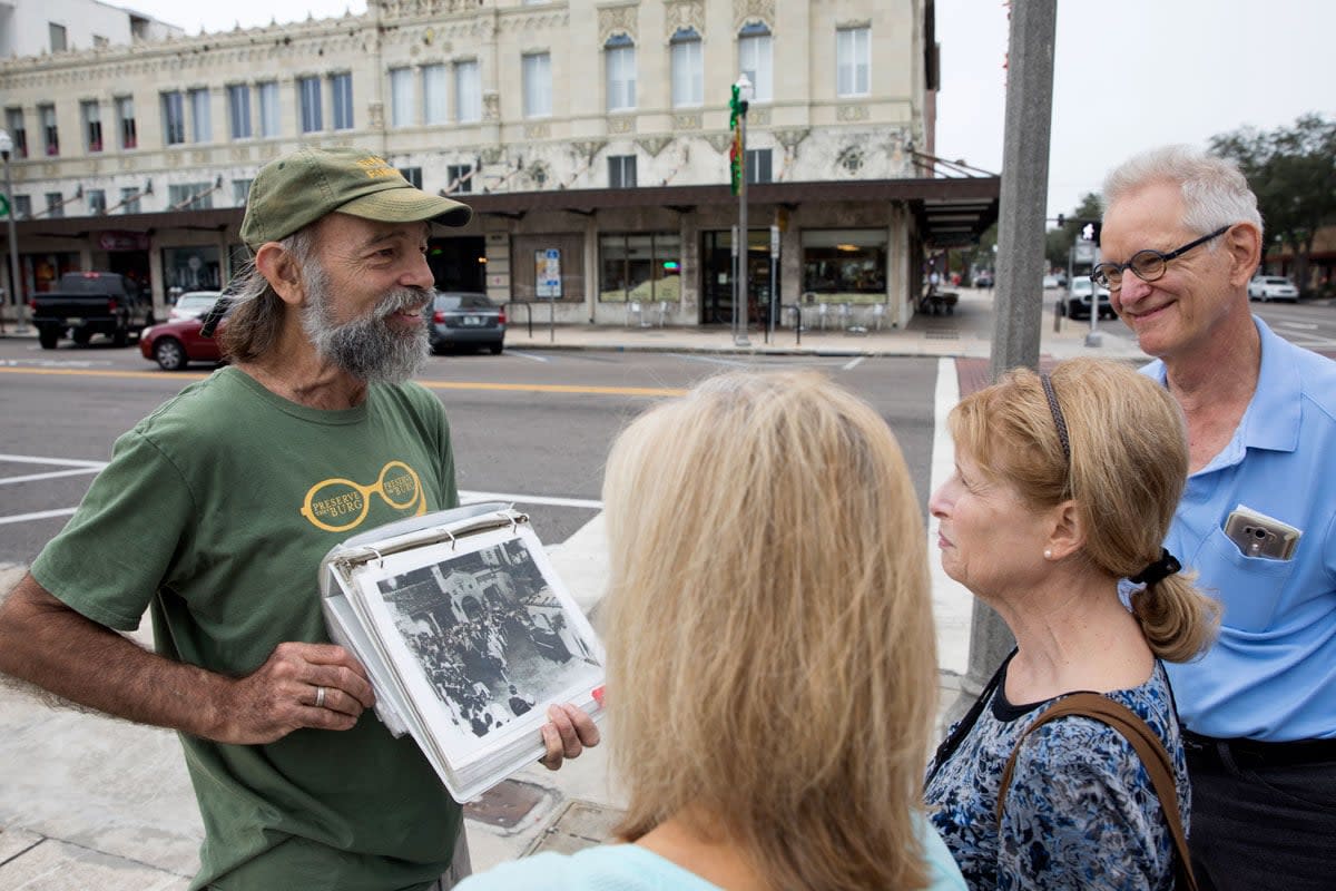 A man gives a guided tour of downtown St. Petersburg to three people. 