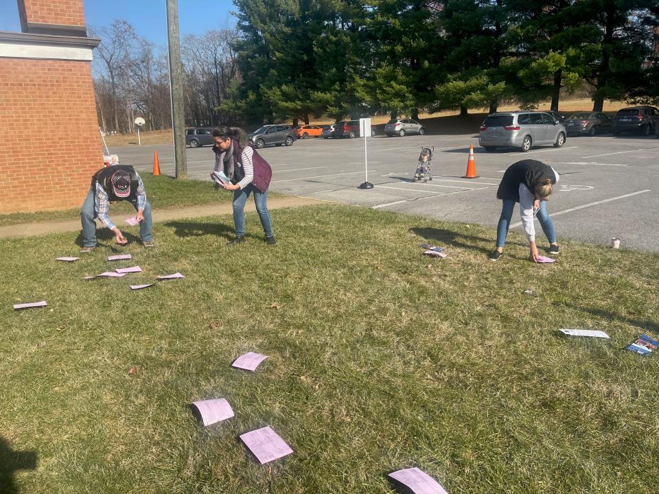 Volunteers from local campaigns and parties pick up the wind-scattered sample ballots and door hangers.