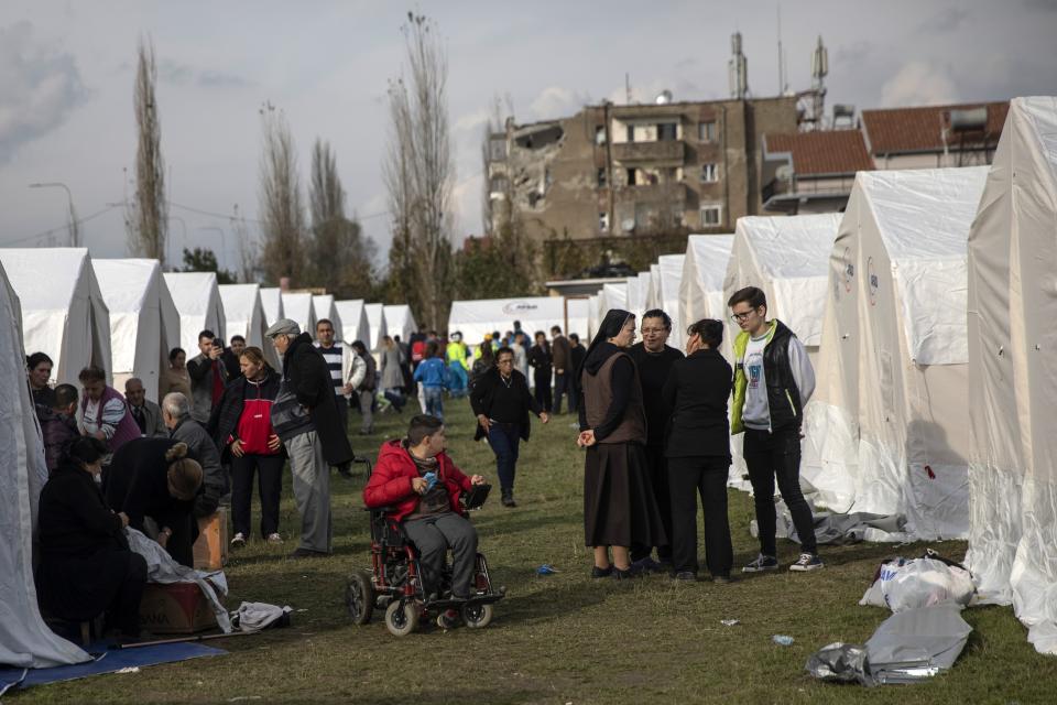 People stand outside their tents at a makeshift camp after an earthquake in Thumane, western Albania, Wednesday, Nov. 27, 2019. Overnight, authorities said four more people had been confirmed dead, and one more death was reported early Wednesday afternoon, raising the death toll to 26, while more than 650 people were injured in the magnitude-6.4 quake that struck the country's coastal cities. (AP Photo/Petros Giannakouris)