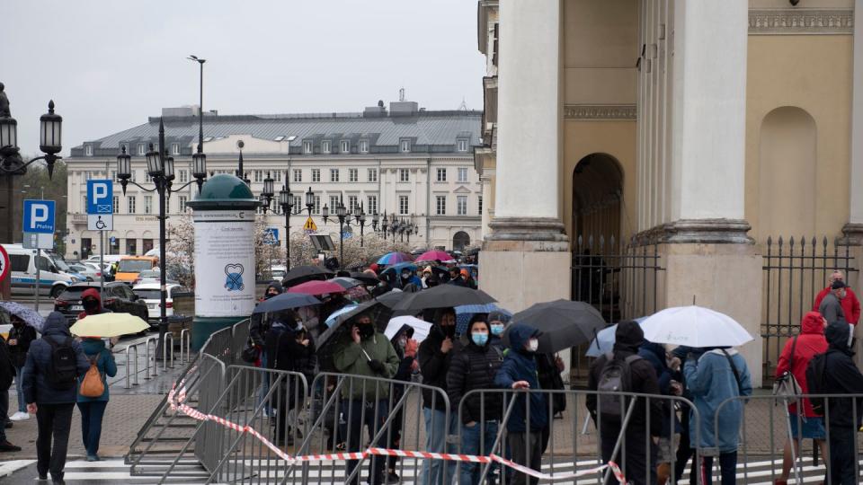 Menschen warten in einer Schlange vor dem Warschauer Rathaus auf ihre Impfung.