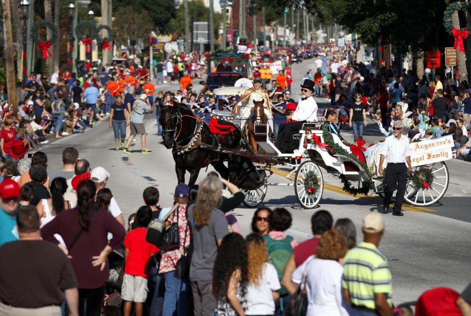 Wearing a black top hat, Murphy McDaniel drives his horse and carriage and St. Augustine's Royal Family in circles as participants travel south on Avenida Menendez near the Old City Gates during the 59th Annual Christmas Parade in December 2013.