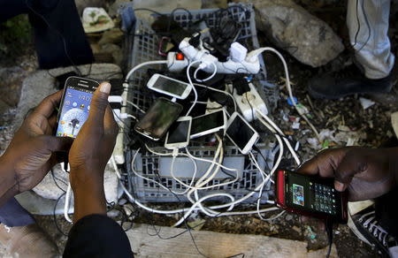 Sudanese immigrants charge their mobile phones at a make-shift electric outlet in the western Greek town of Patras May 4, 2015. REUTERS/Yannis Behrakis