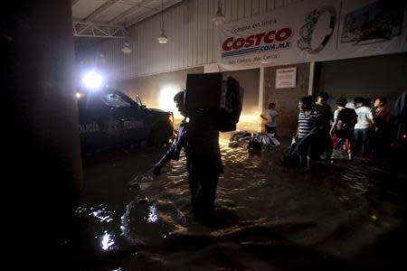 People carry looted goods as they walk through a flooded street in Acapulco September 18, 2013. REUTERS/Jacobo Garcia