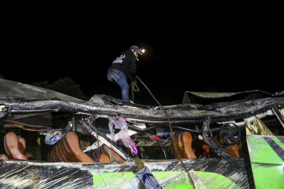 A rescuer stands atop of the wreckage of a bus after an accident in Subang, West Java, Indonesia, late Saturday, May 11, 2024. The bus carrying high school students and teachers returning from an outing smashed into cars and motorbikes in Indonesia's West Java province, killing a number of people on board. (AP Photo/Ryan Suherlan)