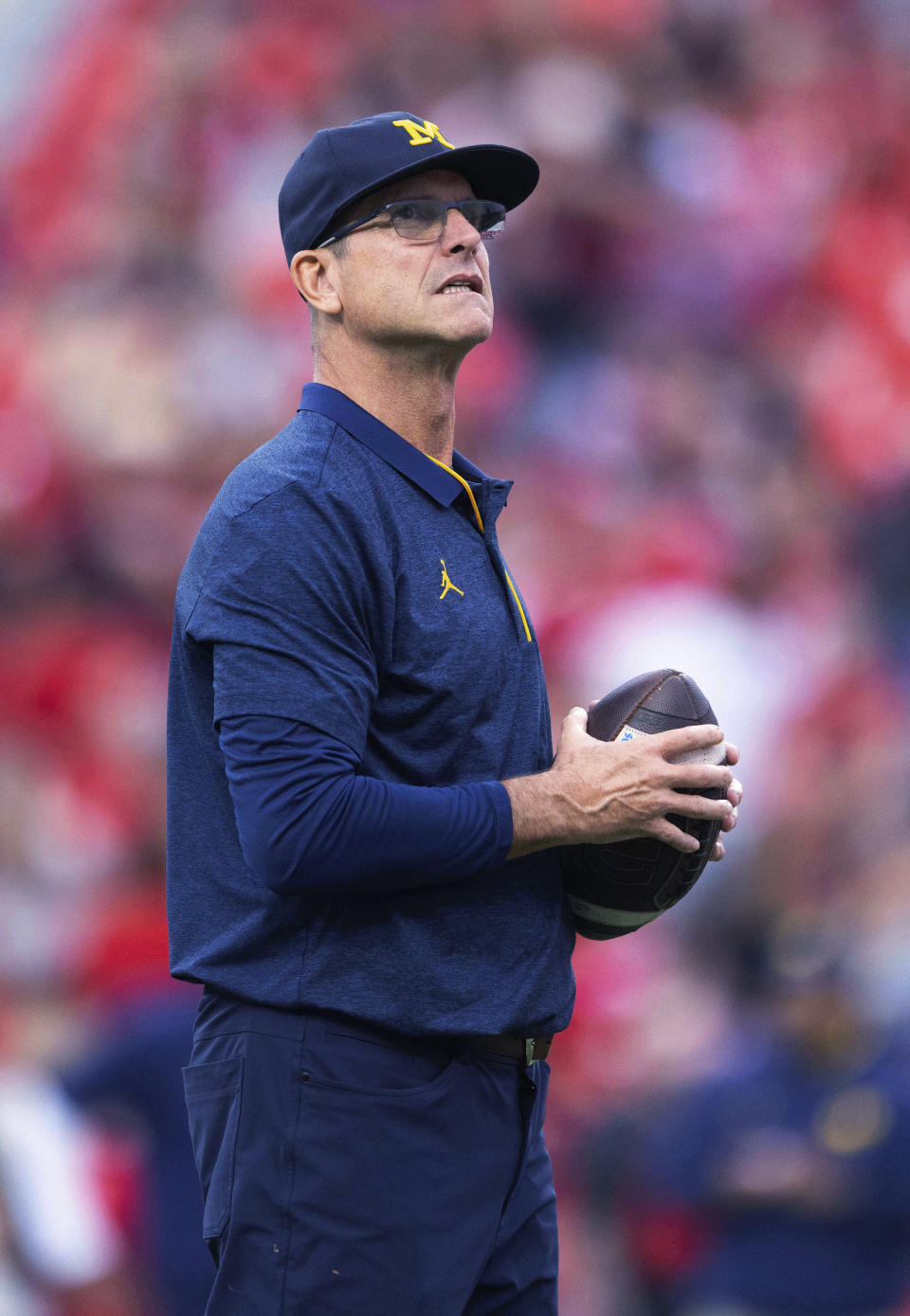 FILE - Michigan coach Jim Harbaugh stands on the field as players warm up for an NCAA college football game against Nebraska on Oct. 9, 2021, at Memorial Stadium in Lincoln, Neb. Harbaugh is The Associated Press college football coach of the year after leading the Wolverines to their first Big Ten title in 17 years and a berth in the College Football Playoff. (AP Photo/Rebecca S. Gratz, File)