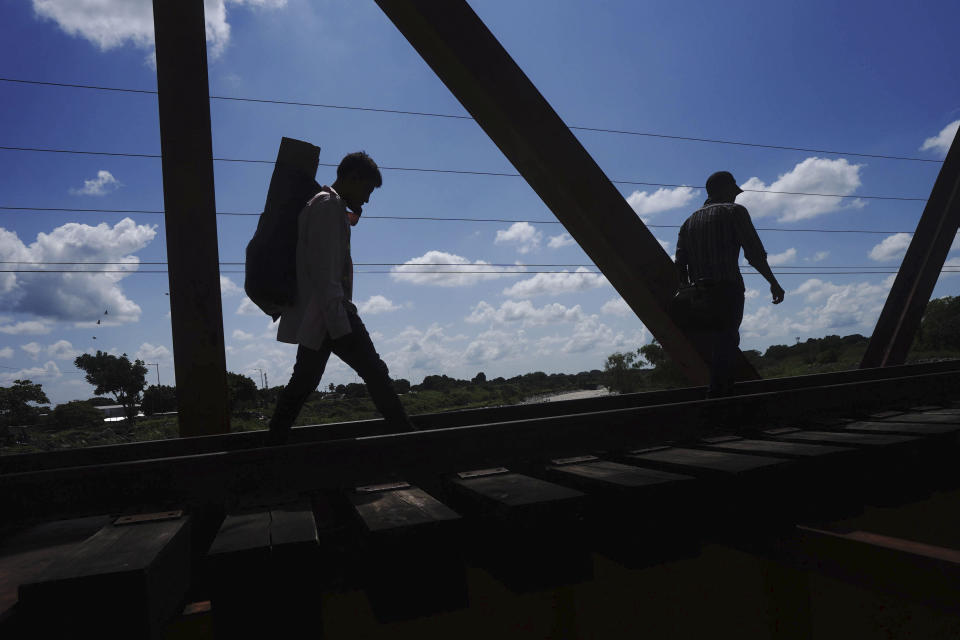 Migrants who are part of caravan cross a railroad track in Huixtla, Chiapas state, Mexico, Tuesday, Oct. 26, 2021, on a day of rest before continuing their trek across southern Mexico to the U.S. border. (AP Photo/Marco Ugarte)