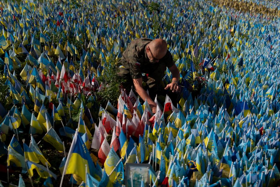 Polish Army veteran Slawomir Wysocki, 50, places the country's flag at a memorial site in Kyiv, Ukraine, Wednesday, July 12, 2023, to honor a Polish paramedic killed in Ukraine's war against Russia.