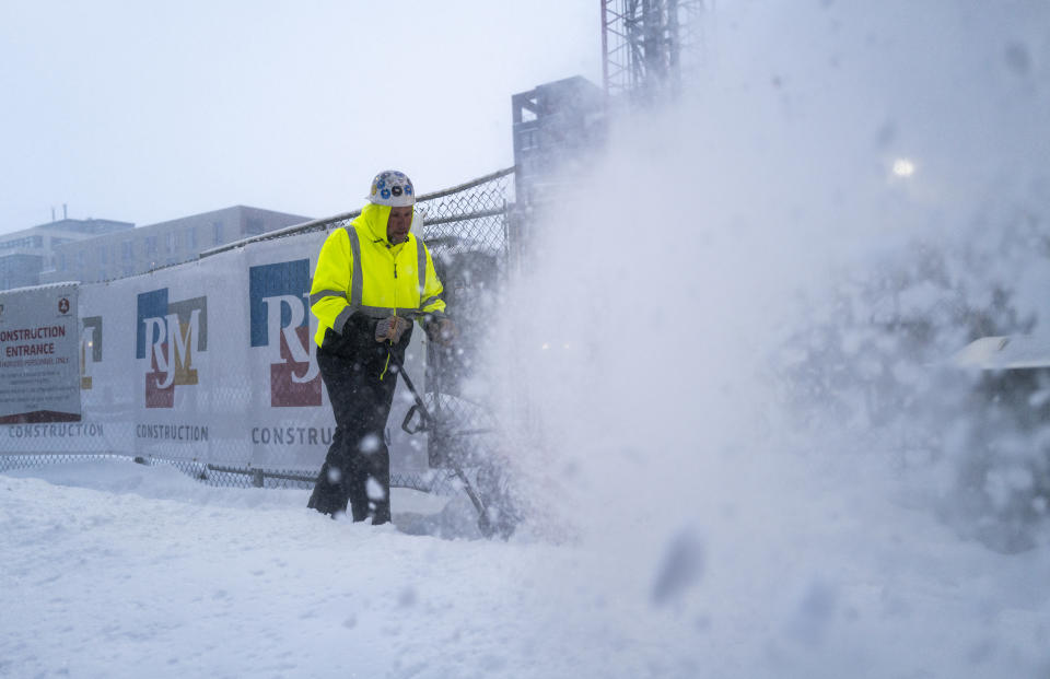 A worker with RJM Construction clears snow from a work site.