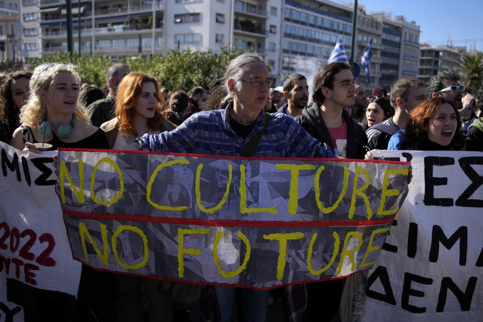 A man holds a banner as students from drama and arts schools shout slogans during a protest outside parliament in Athens, Greece on Thursday, Feb. 2, 2023. Performing artists and arts students are striking for a second day, closing theatres, halting television shoots and disrupting art school classes, to protest charges in the qualification system of civil service jobs. (AP Photo/Thanassis Stavrakis)