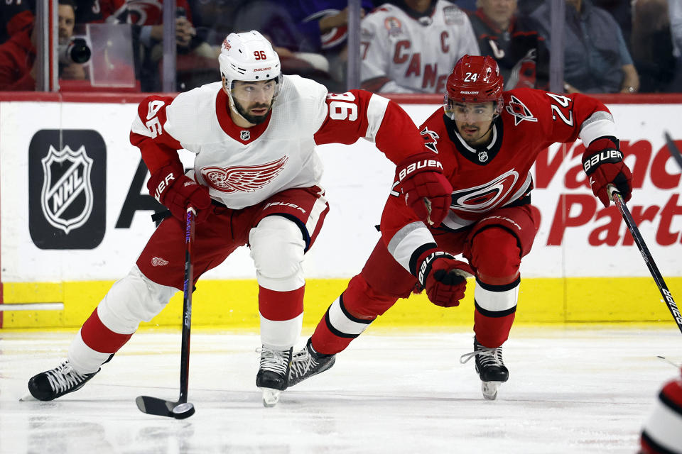 Detroit Red Wings' Jake Walman (96) controls the puck in front of Carolina Hurricanes' Seth Jarvis (24) during the first period of an NHL hockey game in Raleigh, N.C., Tuesday, April 11, 2023. (AP Photo/Karl B DeBlaker)