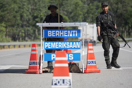 Members of the General Operations Force control the checkpoint on the road near the area where the abandoned human trafficking camp was discovered in the jungle close to the Thailand border at Bukit Wang Burma in northern Malaysia May 28, 2015. REUTERS/Damir Sagolj