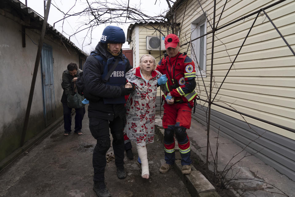 FILE - Associated Press photographer Evgeniy Maloletka helps a paramedic to transport a woman injured during shelling in Mariupol, eastern Ukraine, on March 2, 2022. Maloletka and Mstyslav Chernov, two Ukrainians who documented the horrors of the Russian invasion and siege of Mariupol for The Associated Press, are being honored for their courage with Colby College's Lovejoy Award. (AP Photo/Mstyslav Chernov, File)