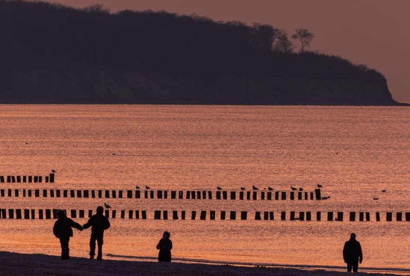 Walkers at sunset on the Baltic Sea beach in Warnemuende. Temperatures in Germany during March were the warmest on record since measurements began in 1881, according to preliminary figures released by the German Weather Service (DWD) on Tuesday. Jens Büttner/dpa