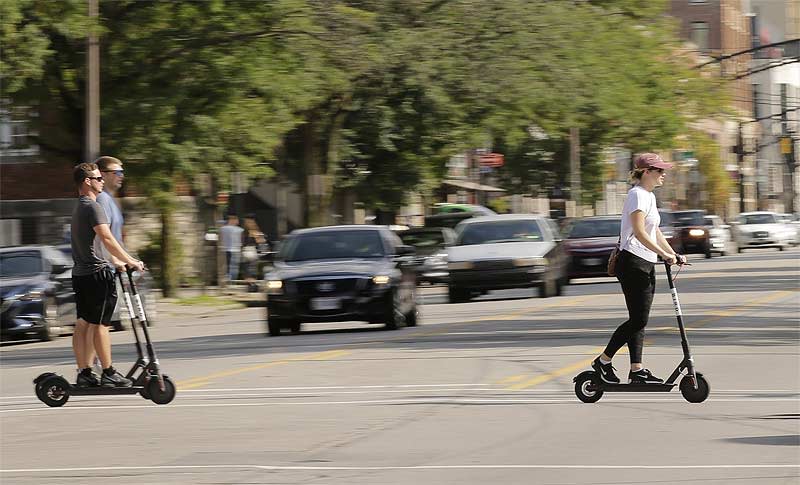 Electric scooters have become a popular means of transportation in U.S. cities. Here riders are seen earlier this month crossing High Street in the Short North. [Adam Cairns/Dispatch]