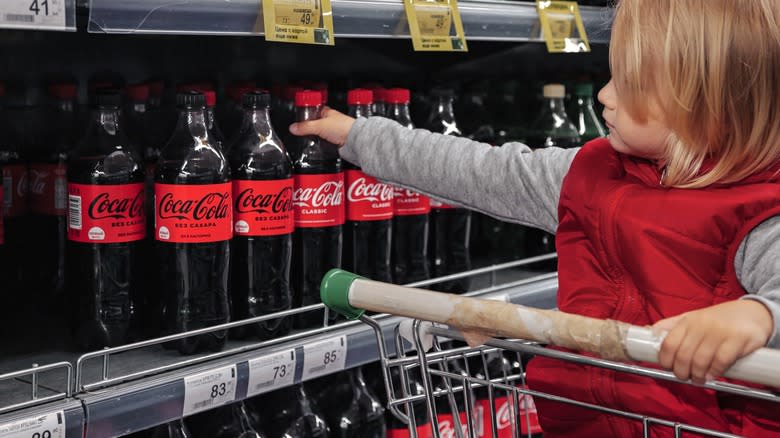 Child reaching for a bottle of Coke