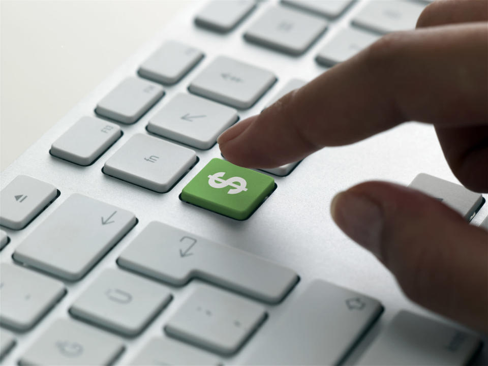 finger about to press green dollar sign key on a keyboard, signifying IT spending in 2022