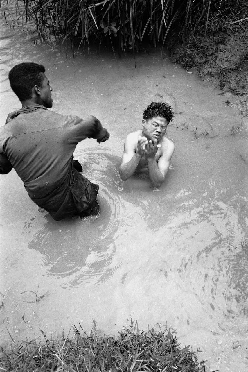 A U.S. soldier hits a Viet Cong prisoner in the face after the guerrilla had been discovered in his underwater hiding place near Bong Son, Feb. 19, 1967. (AP Photo)