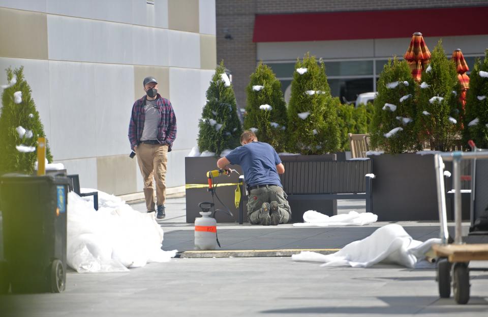 A man uses a tool to create the effect of melted snow in the courtyard of Worcester's AC Hotel by Marriott in May on Front Street.