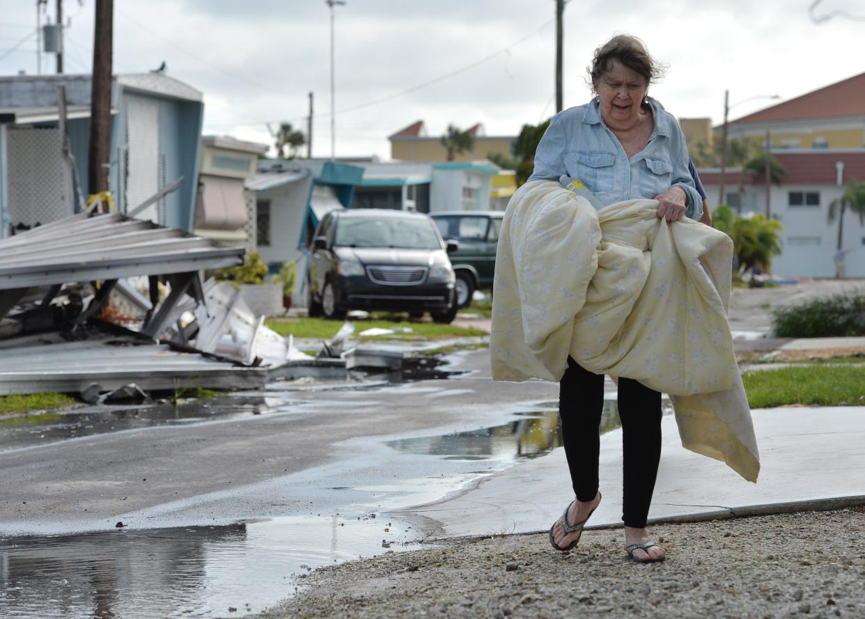 Carol Schoen carries her bedding to her home in the Venice Municipal Mobile Home Park on Sept. 29 after staying overnight in the park's community center during Hurricane Ian.  Schoen lost part of the roof on her mobile home.