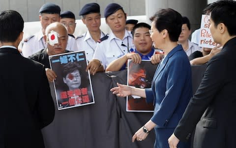 Hong Kong's Chief Executive Carrie Lam walks past protesters outside her office  - Credit: Reuters