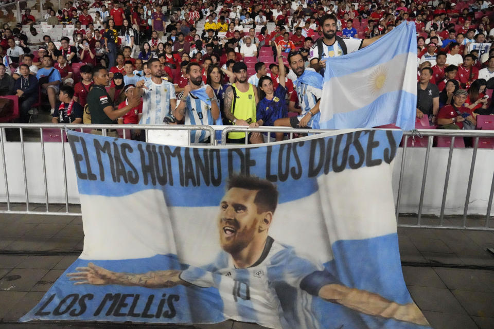 Supporters of Argentina display a flag bearing an image of soccer superstar Lionel Messi bprior to a friendly soccer match against indonesia at Gelora Bung Karno Main Stadium in Jakarta, Indonesia, Monday, June 19, 2023. (AP Photo/Achmad Ibrahim)